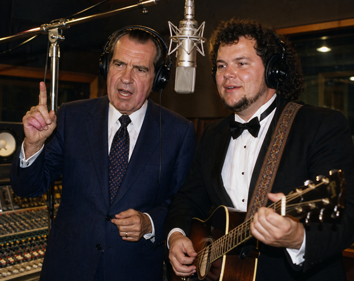 Richard Nixon in a recording studio wearing headphones and singing into a microphone beside a tuxedoed guitarist during a music session.